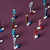 Miniature figures standing among colorful medical capsules illustrating the global scale of antibiotic resistance.