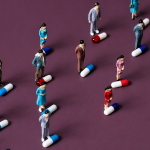 Miniature figures standing among colorful medical capsules illustrating the global scale of antibiotic resistance.