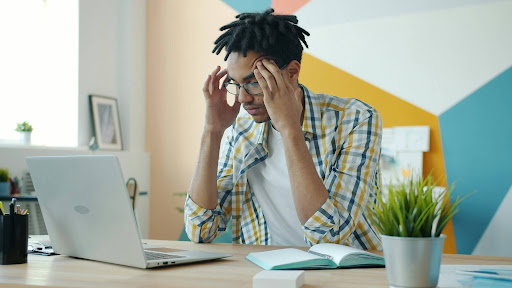 A student studying while having a headache. Image credit: Unsplash